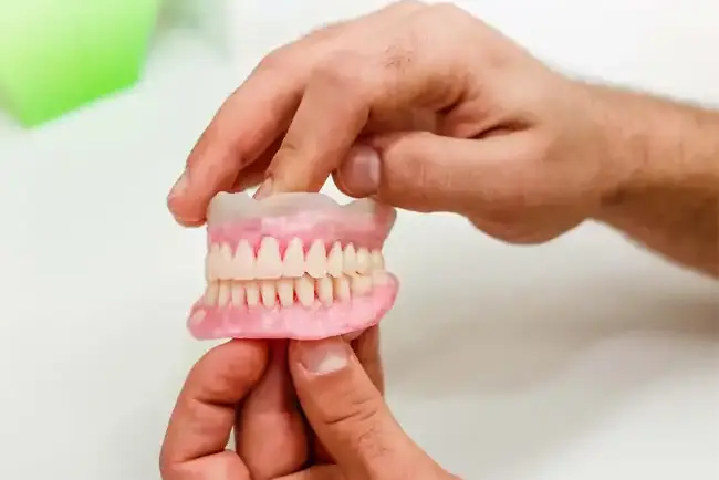 a hand holding a full dentures